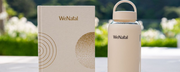 A glass water bottle with a white sleeve next to a white and gold journal - can you drink electrolytes while pregnant - wenatal prenatal vitamins